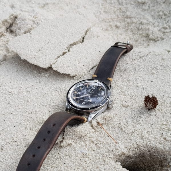 Gurney 1 vintage leather strap by gunny straps with mysterious grey brown color shown on omega seamaster speedmaster wristwatch